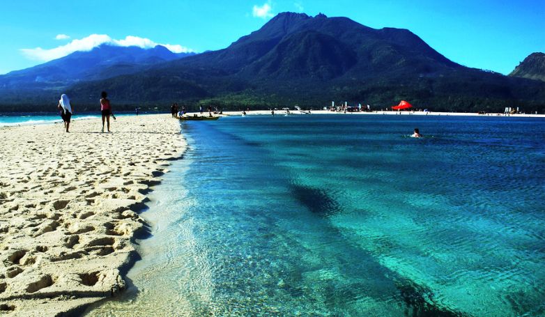 White sand beach with crystal clear water and breathtaking view of the mountain on Camiguin Island