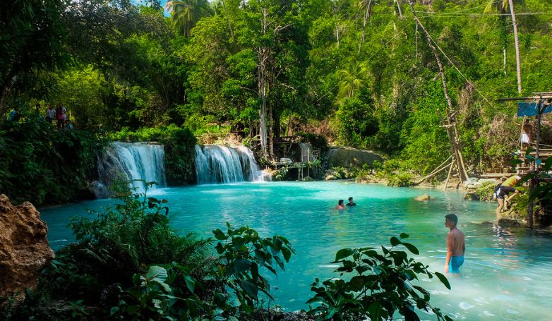 Tourists enjoy swimming on the Cambugahay waterfalls in Siquijor Island