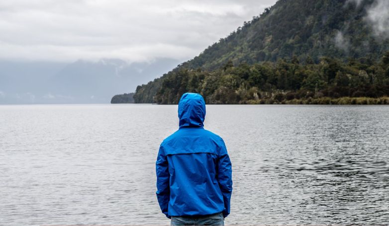 Man wearing a raincoat standing near the sea